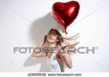 Stock Photo - Woman with red heart-shaped balloon. Fotosearch
