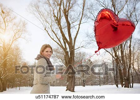 Woman with red heart-shaped balloon View Large Photo Image Stock Photo - Woman with red heart-shaped balloon. Fotosearch