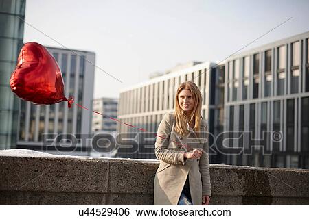Stock Photograph - Woman with red heart-shaped balloon. Fotosearch