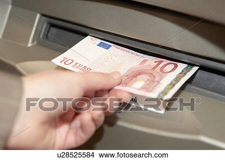 Picture - Woman withdrawing ten euro note from cashpoint. Fotosearch