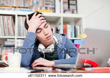 Worried male student with hand in hair using laptop View Large Photo Image Stock Image - Worried male student with hand in hair using laptop. Fotosearch