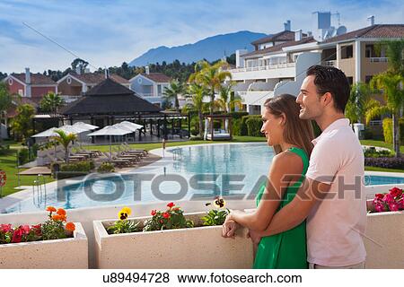 Stock Photo - Young couple looking at view at holiday resort. Fotosearch