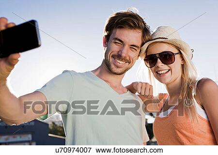 Young couple photographing themselves View Large Photo Image Stock Photo - Young couple photographing themselves. Fotosearch