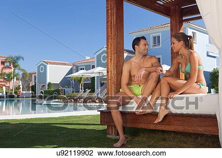 Stock Image - Young couple relaxing on sunlounger at holiday resort. Fotosearch