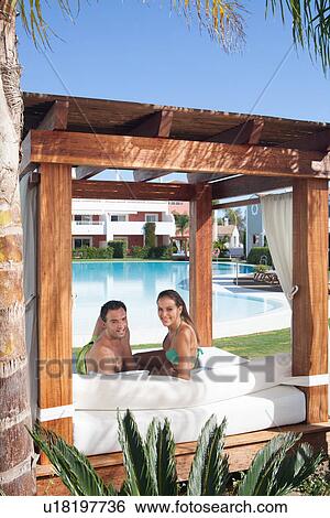 Stock Photograph - Young couple relaxing on sunlounger at holiday resort. Fotosearch