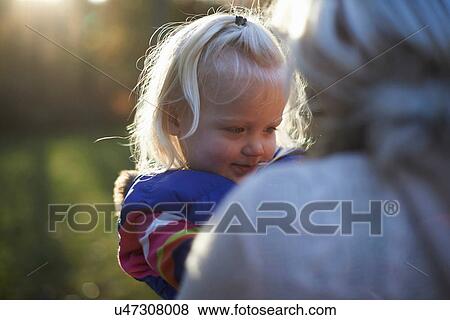 Young girl with mother outdoors in sunlight, close up View Large Photo Image Stock Photo - Young girl with mother outdoors in sunlight, close up. Fotosearch