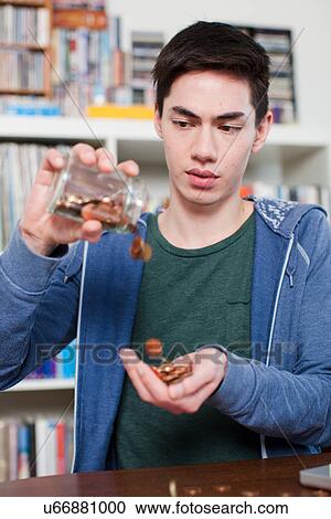Young man emptying jar of coins View Large Photo Image Stock Image - Young man emptying jar of coins. Fotosearch