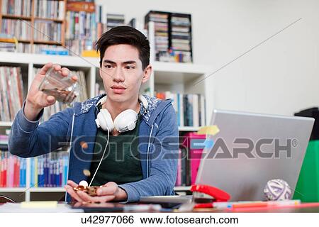 Young man emptying jar of coins View Large Photo Image Stock Photograph - Young man emptying jar of coins. Fotosearch