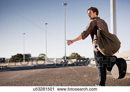 Stock Image - Young man hitch hiking. Fotosearch