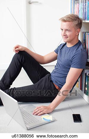 Stock Photograph - Young man sitting on floor using laptop. Fotosearch