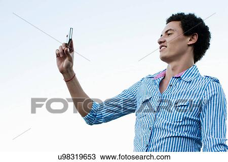 Stock Image - Young man taking a picture of himself. Fotosearch