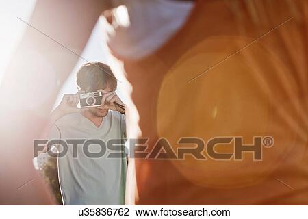 Stock Image - Young man taking pictures. Fotosearch