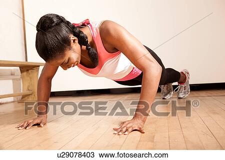 Stock Image - Young woman doing press ups. Fotosearch