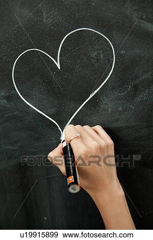 Young woman drawing heart on blackboard View Large Photo Image Stock Photo - Young woman drawing heart on blackboard. Fotosearch