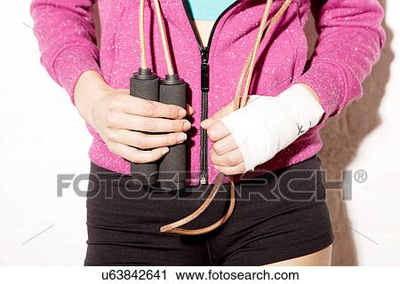 Stock Image - Young woman holding skipping rope. Fotosearch