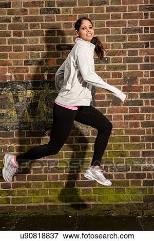 Young woman jumping by brick wall View Large Photo Image Stock Photo - Young woman jumping by brick wall. Fotosearch