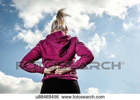 Stock Photograph - Young woman stretching with hands behind back. Fotosearch