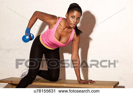 Stock Image - Young woman using hand weight. Fotosearch