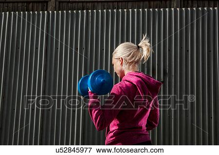 Young woman using hand weights by building View Large Photo Image Stock Photo - Young woman using hand weights by building. Fotosearch