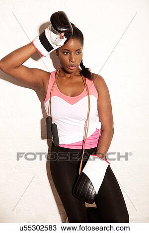 Stock Image - Young woman wearing boxing gloves. Fotosearch