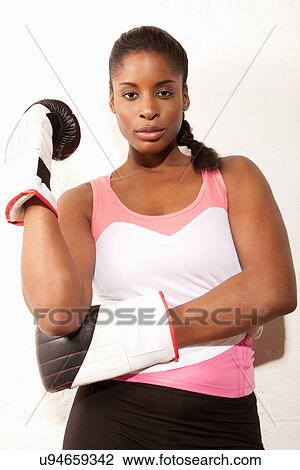 Stock Image - Young woman wearing boxing gloves. Fotosearch