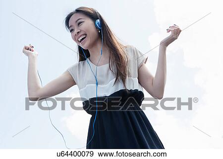 Stock Photo - Young woman wearing headphones dancing. Fotosearch