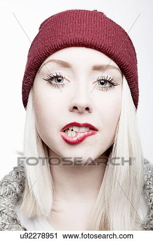 Stock Image - Young woman wearing red hat biting lip. Fotosearch