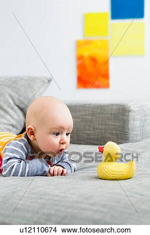 Picture - Baby boy staring at rubber duck. Fotosearch