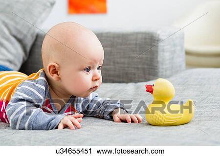 Stock Image - Baby boy staring at rubber duck. Fotosearch