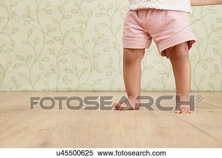 Stock Photography - Baby girl taking first steps, low section. Fotosearch