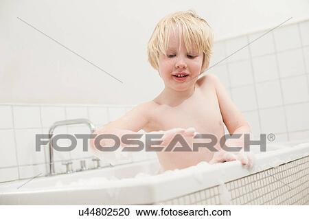 Stock Image - Boy looking at soapsuds in the bathtub. Fotosearch