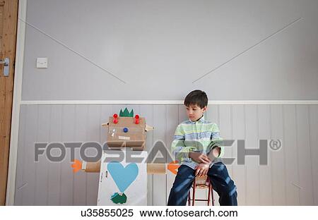 Boy sitting next to homemade toy robot View Large Photo Image Stock Photography - Boy sitting next to homemade toy robot. Fotosearch