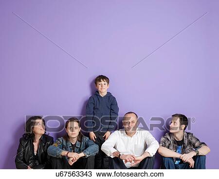 Boy standing in the middle of sitting family in front of purple background View Large Photo Image Stock Image - Boy standing in the middle of sitting family in front of purple background. Fotosearch