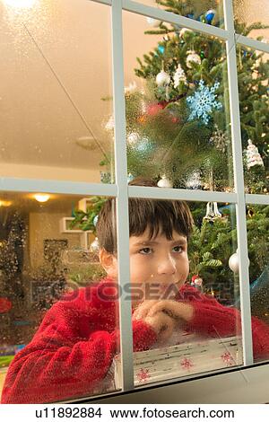 Picture - Boy staring out of window on christmas eve. Fotosearch