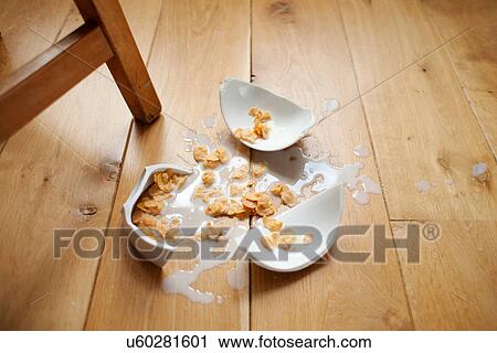 Stock Image - Broken bowl of cereal on wooden floor. Fotosearch