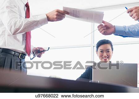 Businessman handing colleague document in office View Large Photo Image Stock Image - Businessman handing colleague document in office. Fotosearch