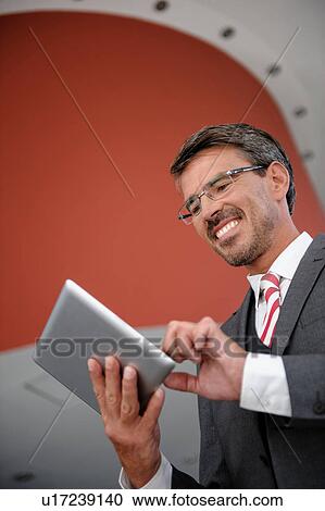 Stock Image - Businessman looking at digital tablet. Fotosearch