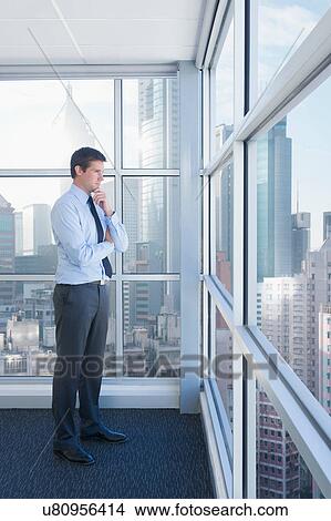 Businessman looking out of office window View Large Photo Image Picture - Businessman looking out of office window. Fotosearch