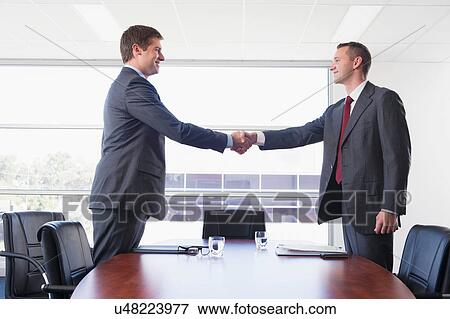 Businessmen shaking hands above desk View Large Photo Image Stock Photo - Businessmen shaking hands above desk. Fotosearch