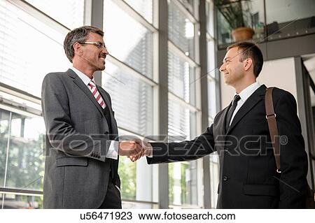 Businessmen shaking hands in lobby View Large Photo Image Stock Image - Businessmen shaking hands in lobby. Fotosearch