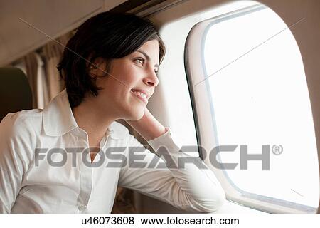 Stock Photo - Candid portrait of young female looking out of aeroplane window. Fotosearch