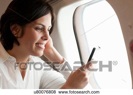 Candid portrait of young female looking at smartphone on aeroplane View Large Photo Image Stock Photo - Candid portrait of young female looking at smartphone on aeroplane. Fotosearch