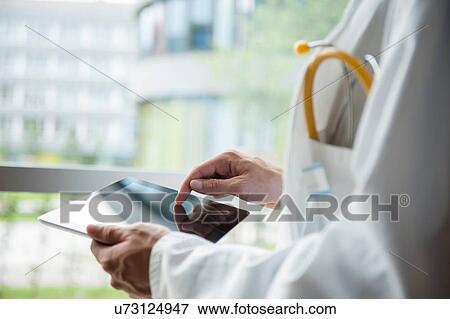 Stock Photo - Close up of young male doctor using digital tablet. Fotosearch