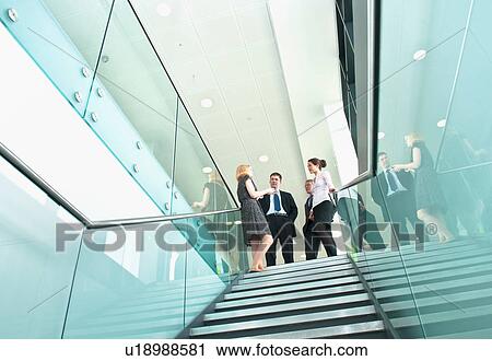 Colleagues standing on staircase in office building View Large Photo Image Stock Image - Colleagues standing on staircase in office building. Fotosearch