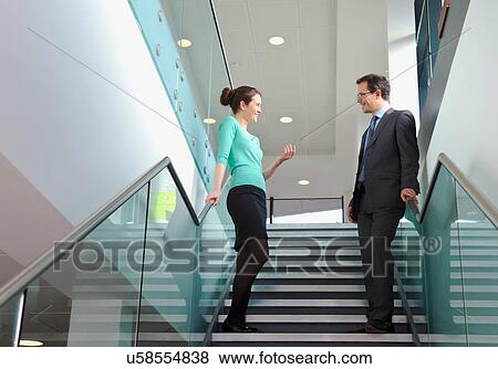 Stock Photo - Colleagues standing on staircase in office building. Fotosearch