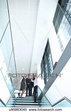 Colleagues standing on staircase in office building View Large Photo Image Stock Photography - Colleagues standing on staircase in office building. Fotosearch