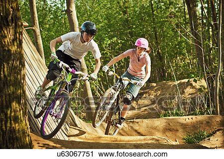 Stock Image - Cyclists riding on dirt bike course. Fotosearch