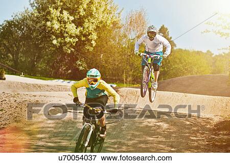 Stock Photo - Cyclists riding on dirt bike course. Fotosearch