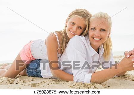 Daughter lying on top of mother on beach View Large Photo Image Stock Photography - Daughter lying on top of mother on beach. Fotosearch
