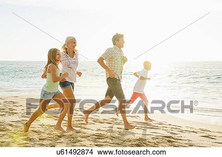 Picture - Family jogging on beach. Fotosearch